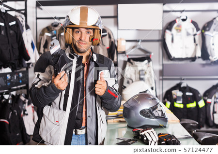 customer in jacket with helmet is choosing gloves customer in jacket with helmet is choosing gloves 57124477