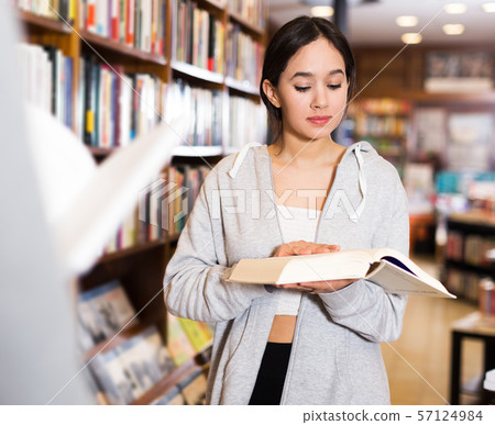 girl browsing textbooks in bookstore girl browsing textbooks in bookstore 57124984