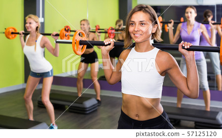 Portrait of sporty women exercising with barbell in fitness club Portrait of sporty women exercising with barbell in fitness club 57125120