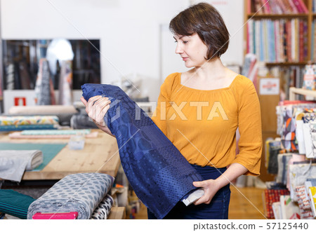 Woman choosing textiles in shop 57125440