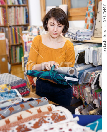 Brunette choosing fabric in store Brunette choosing fabric in store 57125447