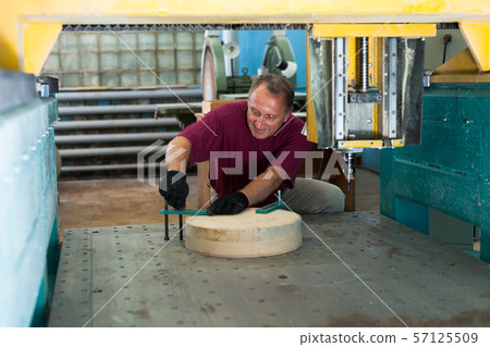 Elderly worker fixes wooden workpiece in 3d machine Elderly worker fixes wooden workpiece in 3d machine 57125509