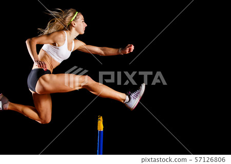 Sportswoman jumping over hurdle on sprint race Sportswoman jumping over hurdle on sprint race 57126806