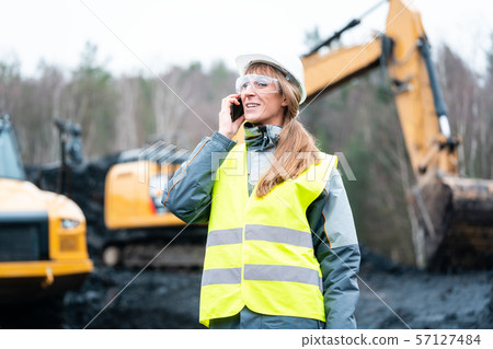 Worker woman in open-cast mining using phone 57127484