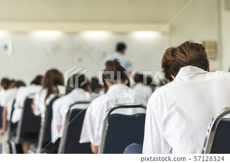 Blur school background university students writing answer doing exam in classroom . 57128324