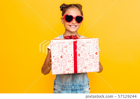 Shocked young girl, a teenager holds a gift box in Shocked young girl, a teenager holds a gift box in 57129244