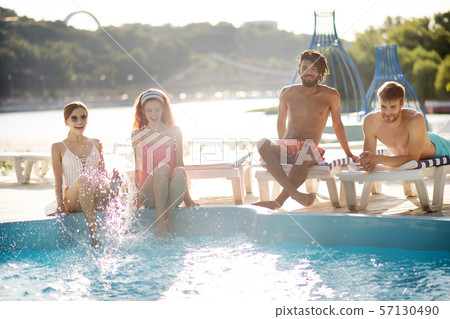 Young women putting feet in water while chilling near pool 57130490