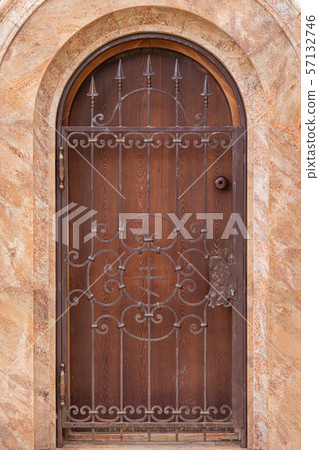 Close-up of church window behind wrought iron grid in red marble wall Close-up of church window behind wrought iron grid in red marble wall 57132746