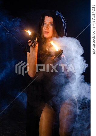 Young girl in a long black coat fire night. Young girl in a long black coat fire night. 57134233