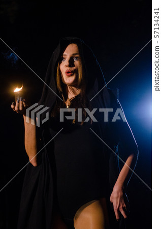 Young girl in a long black coat fire night Young girl in a long black coat fire night 57134241