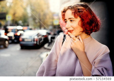 Beautiful woman with red dyed hair and sunny city background. Beautiful woman with red dyed hair and sunny city background. 57134569