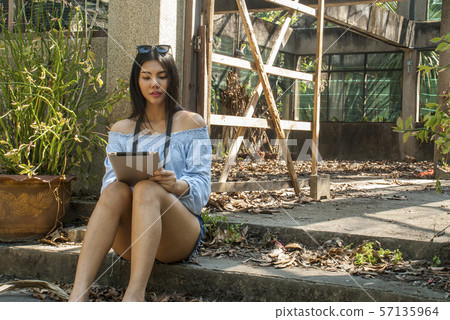 A beautiful woman is watching a tablet while A beautiful woman is watching a tablet while 57135964