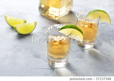 Golden tequila shots with lime slices, salt, a bottle, and a place for text 57137386