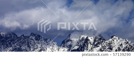 High snowy mountains in clouds at sunny day High snowy mountains in clouds at sunny day 57139290