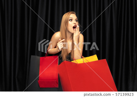 Young woman in dress shopping on black background 57139923