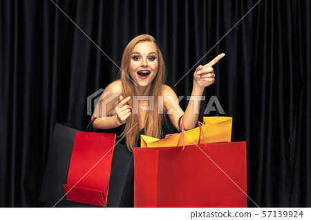 Young woman in dress shopping on black background Young woman in dress shopping on black background 57139924