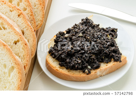 Tapenade sandwich on a sauser and sliced bread 57142798