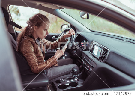 woman driving car, selects navigation on phone s display screen, turns voice assistant, searches for woman driving car, selects navigation on phone s display screen, turns voice assistant, searches for 57142972