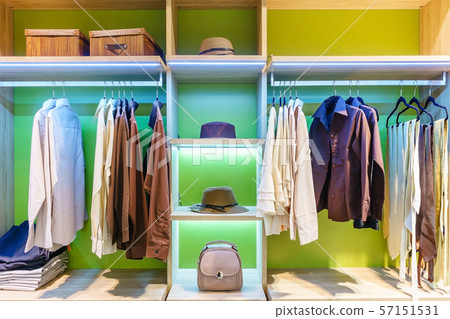 modern wooden wardrobe with clothes hanging on rail in walk in closet 57151531