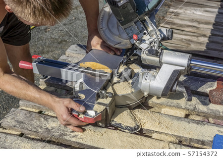 A carpenter saws off a board with circular saw A carpenter saws off a board with circular saw 57154372