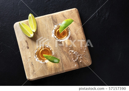 Golden tequila shots with salt and lime slices, shot from above on a black background with copy Golden tequila shots with salt and lime slices, shot from above on a black background with copy 57157390