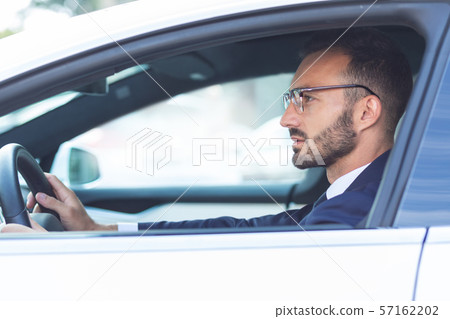 Bearded man holding steering wheel while driving car 57162202