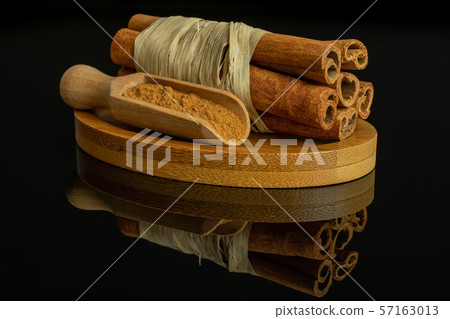 Dry brown cinnamon isolated on black glass Dry brown cinnamon isolated on black glass 57163013