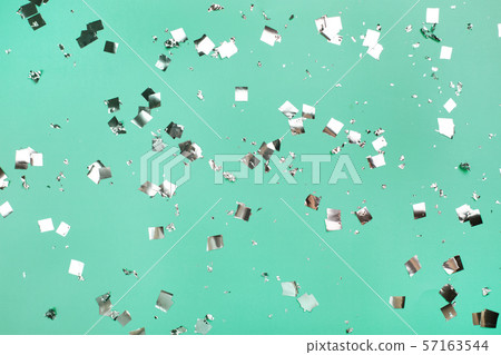 Falling silver confetti on mint backdrop. Falling silver confetti on mint backdrop. 57163544