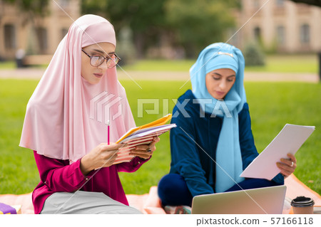 Beautiful muslim student wearing glasses studying with friend Beautiful muslim student wearing glasses studying with friend 57166118