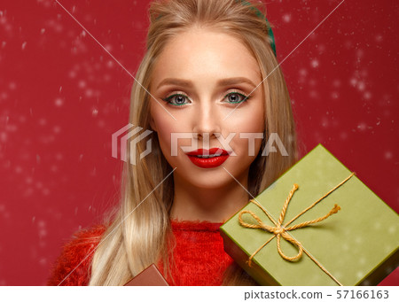 Beautiful blonde girl in a New Year's image with boxes of gifts in hands. Beauty face with festive Beautiful blonde girl in a New Year's image with boxes of gifts in hands. Beauty face with festive 57166163