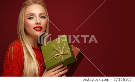 Beautiful blonde girl in a New Year's image with boxes of gifts in hands. Beauty face with festive 57166165