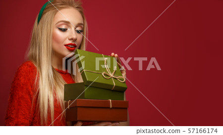 Beautiful blonde girl in a New Year's image with boxes of gifts in hands. Beauty face with festive Beautiful blonde girl in a New Year's image with boxes of gifts in hands. Beauty face with festive 57166174
