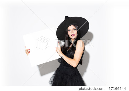 Young woman in hat and dress as a witch on white background 57166244