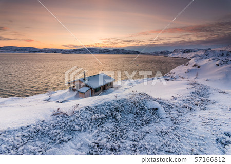 Cottage on the shore of the Arctic Ocean at sunset in winter 57166812