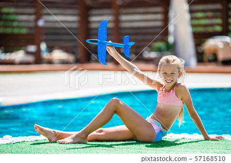 Beautiful little girl having fun near an outdoor pool 57168510