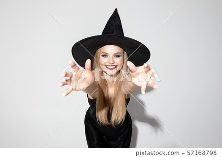 Young woman in hat as a witch on white background 57168798