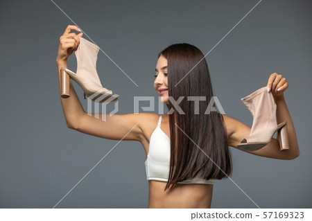 Beautiful young Woman holding heels shoes Beautiful young Woman holding heels shoes 57169323
