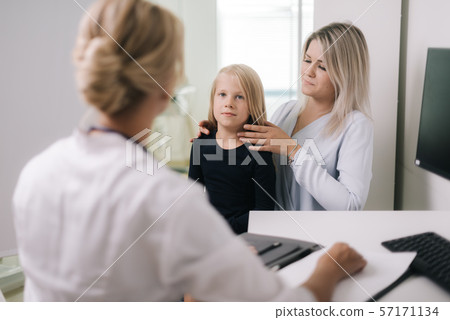 Mom with kid girl with blond hair at doctor in pediatrician appointment. 57171134