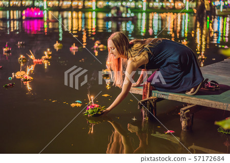 A female tourist holds the Loy Krathong in her hands and is about to launch it into the water. Loy 57172684