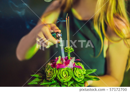 A female tourist holds the Loy Krathong in her hands and is about to launch it into the water. Loy 57172700