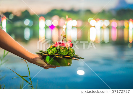 A female tourist holds the Loy Krathong in her hands and is about to launch it into the water. Loy 57172737