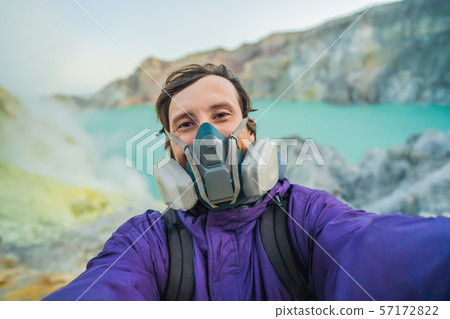 Young man tourist makes a selfie standing at the edge of the crater of the Ijen volcano or Kawah 57172822
