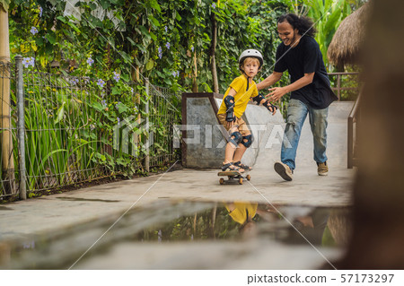 Athletic boy learns to skateboard with asian trainer in a skate park. Children education, sports 57173297