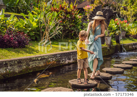 Mom and son tourists in Taman Tirtagangga, Water palace, Water park, Bali Indonesia. Traveling with Mom and son tourists in Taman Tirtagangga, Water palace, Water park, Bali Indonesia. Traveling with 57173346