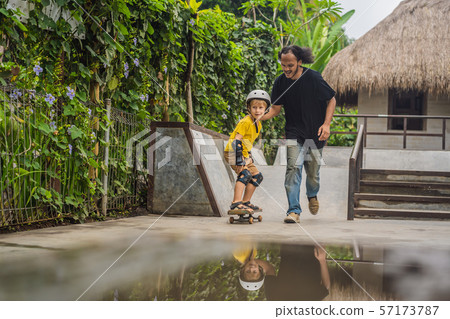 Athletic boy learns to skateboard with asian trainer in a skate park. Children education, sports 57173787