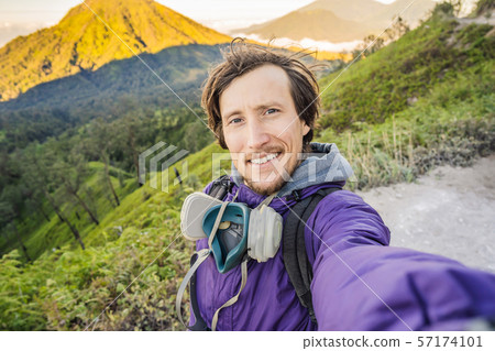 Young man tourist makes a selfie with the magnificent views on green mountains from a mountain road Young man tourist makes a selfie with the magnificent views on green mountains from a mountain road 57174101