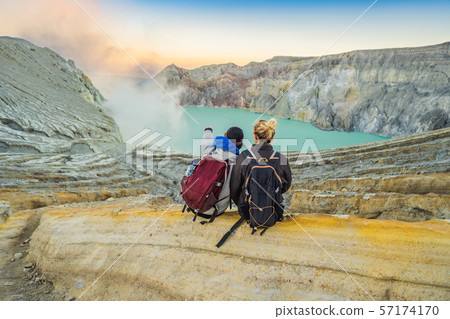 Young tourist man and woman sit at the edge of the crater of the Ijen volcano or Kawah Ijen on the Young tourist man and woman sit at the edge of the crater of the Ijen volcano or Kawah Ijen on the 57174170
