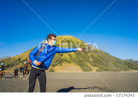 Young man tourist touches volcanic sand in the Bromo Tengger Semeru National Park on the Java Island 57174343