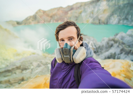 Young man tourist makes a selfie standing at the edge of the crater of the Ijen volcano or Kawah Young man tourist makes a selfie standing at the edge of the crater of the Ijen volcano or Kawah 57174424