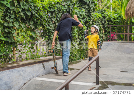 Athletic boy learns to skateboard with a trainer in a skate park. Children education, sports 57174771